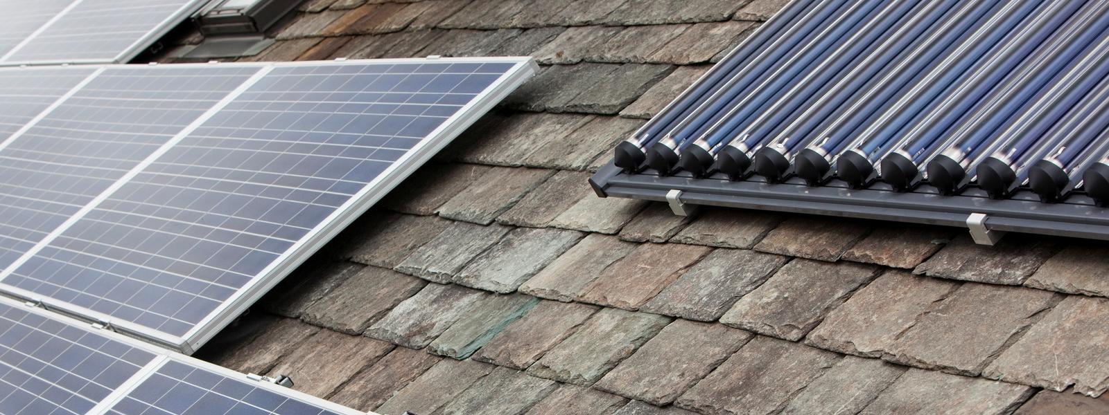 Solar voltaic electricity generating panels and solar hot water panels on a house roof in Ambleside, Cumbria, UK.