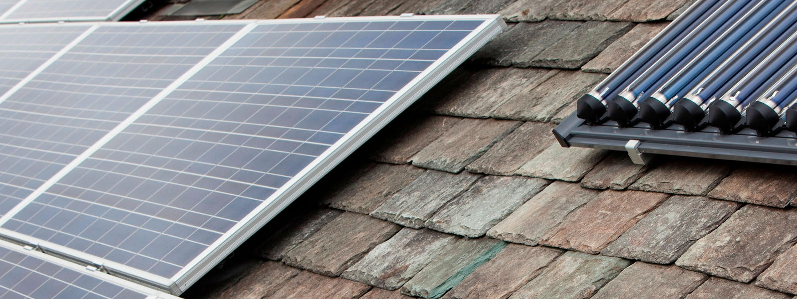 Solar voltaic electricity generating panels and solar hot water panels on a house roof in Ambleside, Cumbria, UK.