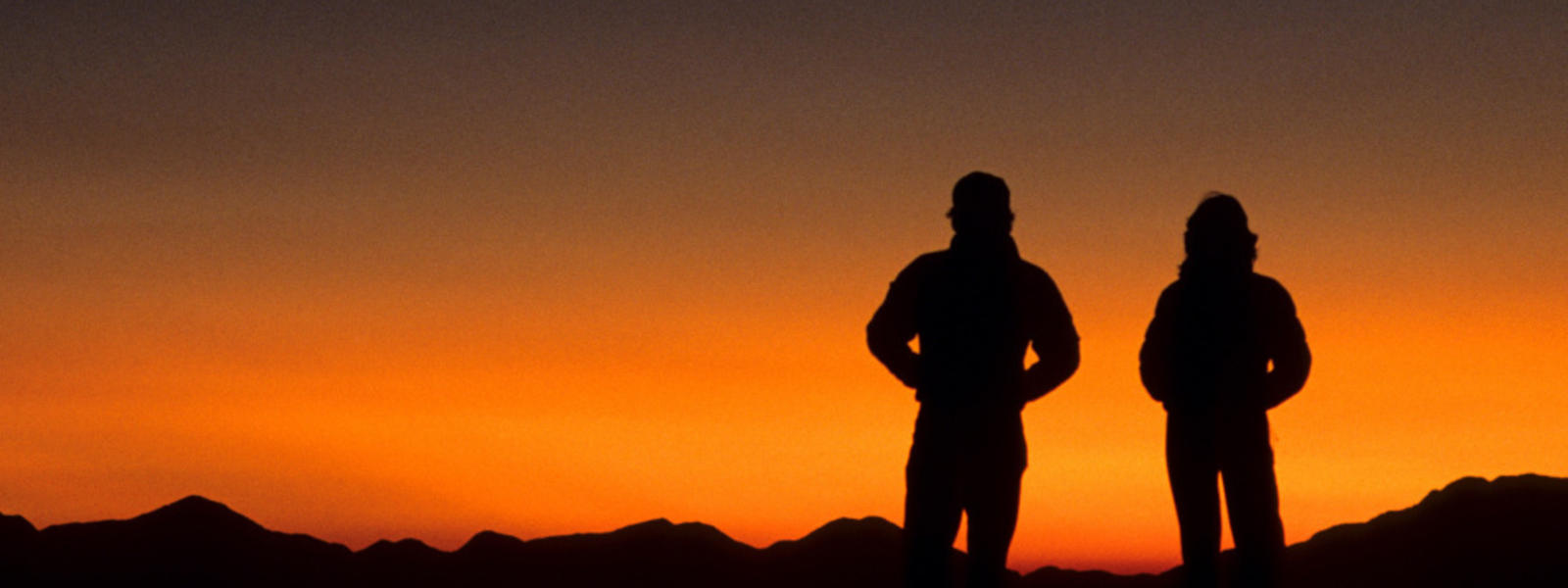 Two hikers silhouetted at sunset, Austrian camp, Dhampus. Annapurna Area, Nepal.