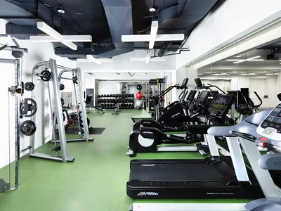 A room with a green floor and black ceiling filled with a variety of workout equipment