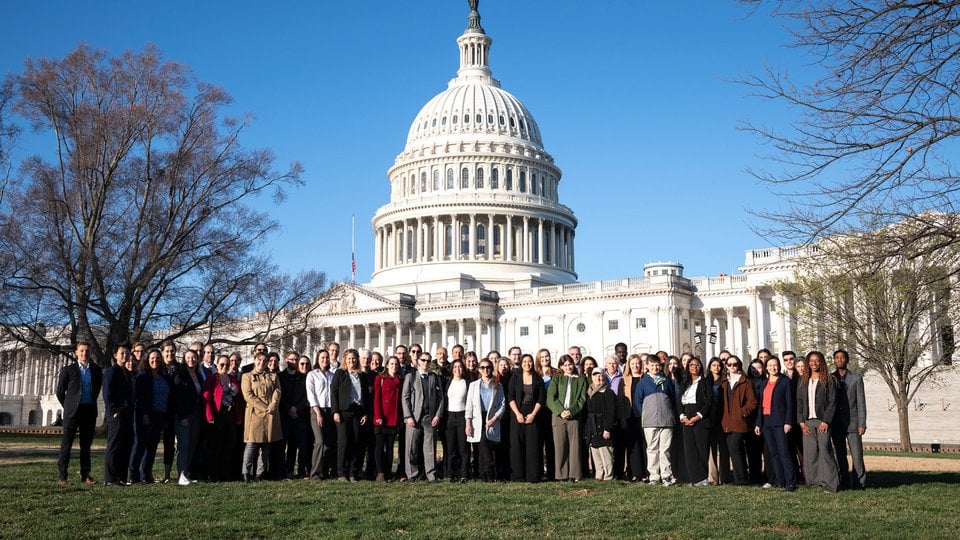A group of people posed in front of the US Capitol
