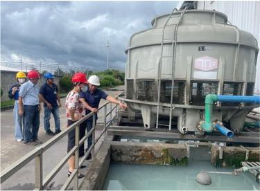 Workers point to a water reservoir at a textile factory