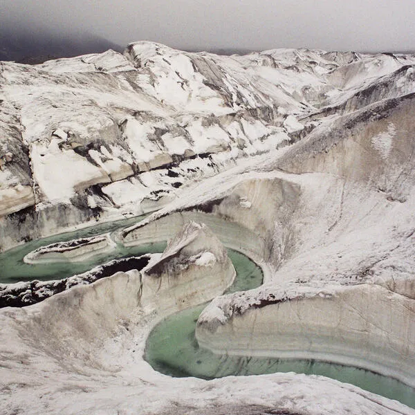 An aerial photo of a sandy mountain range with a river winding through it.