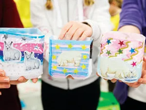 A closeup image of children holding arts and craft style polar bear lanterns