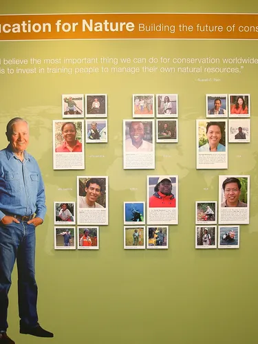 Russell E. Train standing before a wall celebrating WFN grantees