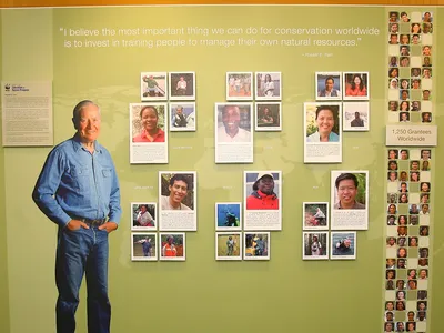 Russell E. Train standing before a wall celebrating WFN grantees