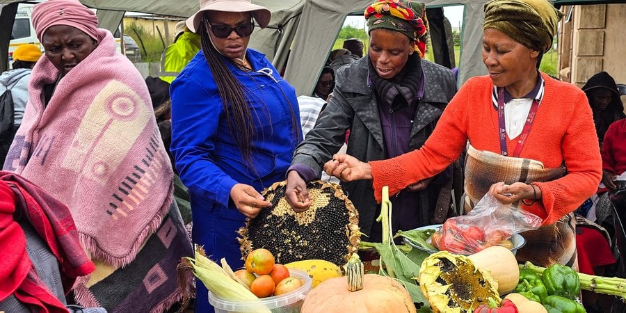 Mme Jonas shows produce from her homestead garden to other women from her village