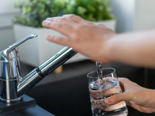 Woman's hand turns off the tap in the kitchen