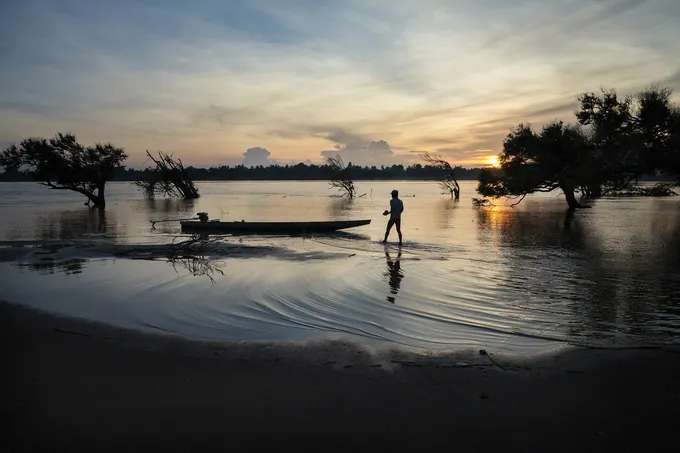 Fisherman cleaning boat at sunset