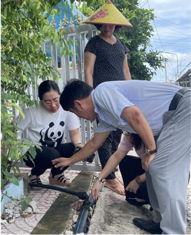 Three people examine a water pipe