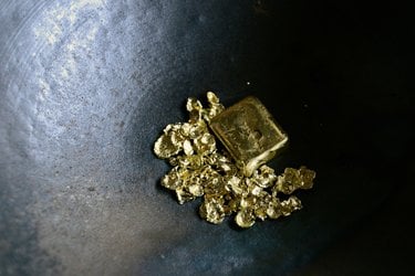 Shiny pieces of gold sit in a black bucket