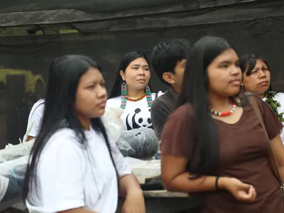 Women of the  Indigenous Paiter Surui community in the Brazilian Amazon listen to a speaker