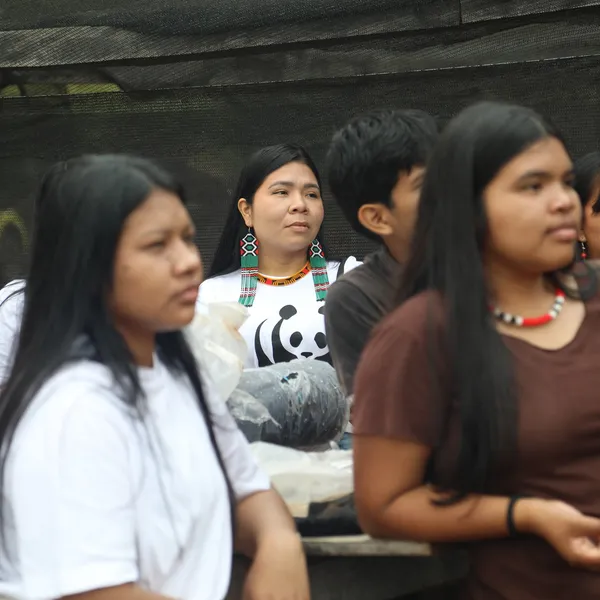 Women of the  Indigenous Paiter Surui community in the Brazilian Amazon listen to a speaker