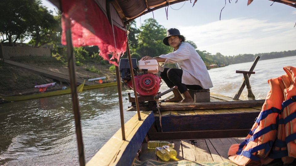 A boatman crouches in the bow