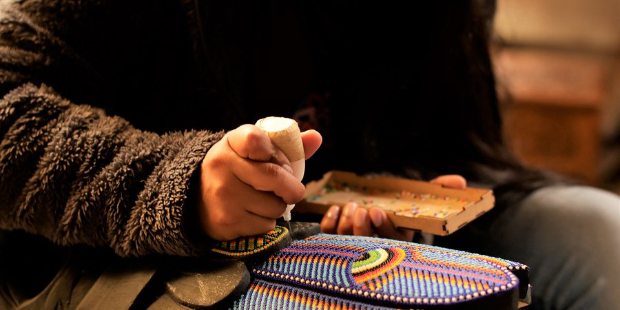 Close-up of hands beading a multi-colored mask
