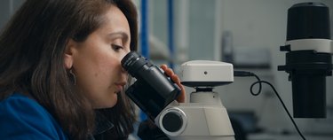 A woman looking into a microscope.