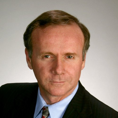 A headshot of a formally dressed man staring at the camera