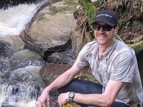A man sits next to a rushing river