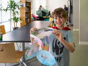 A child in a WWF tshirt holding a crafted umbrella.