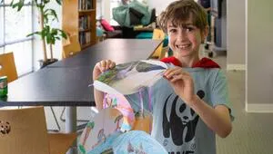A child in a WWF tshirt holding a crafted umbrella.