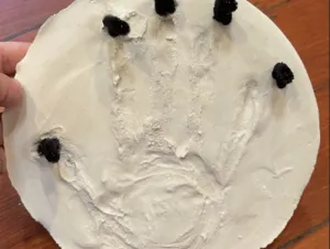 A craft featuring a hand print on plaster.