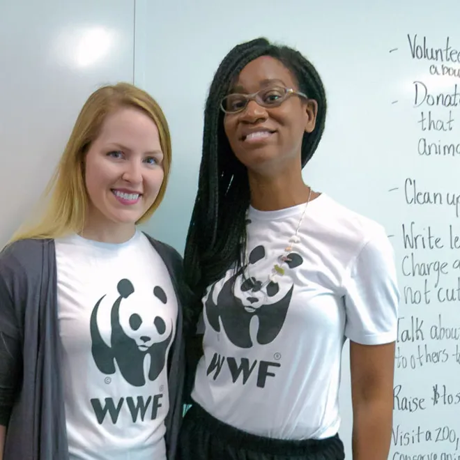 Two women standing in classroom wearing WWF shirts