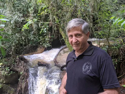 A man stands in front of a waterfall