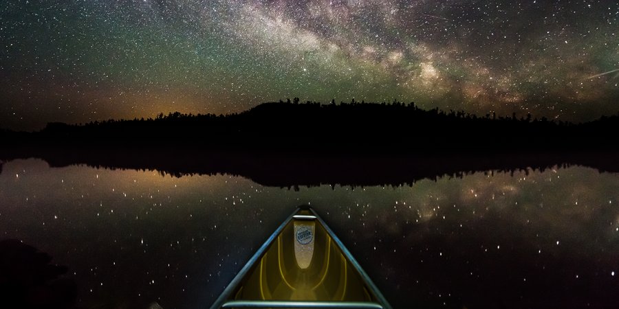 Night photo of stars above the prow of a canoe