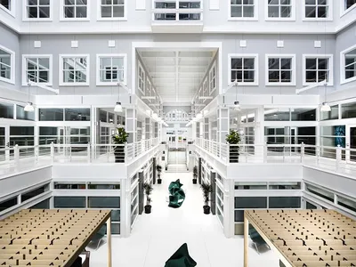 A large building atrium featuring gray and white walls, teal furniture and wood details