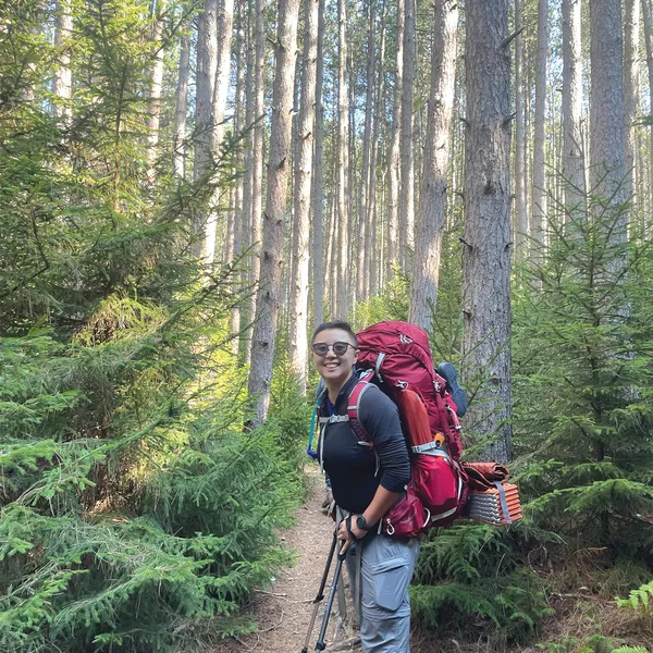 Jeamme Chia hiking in the woods with a large backpack