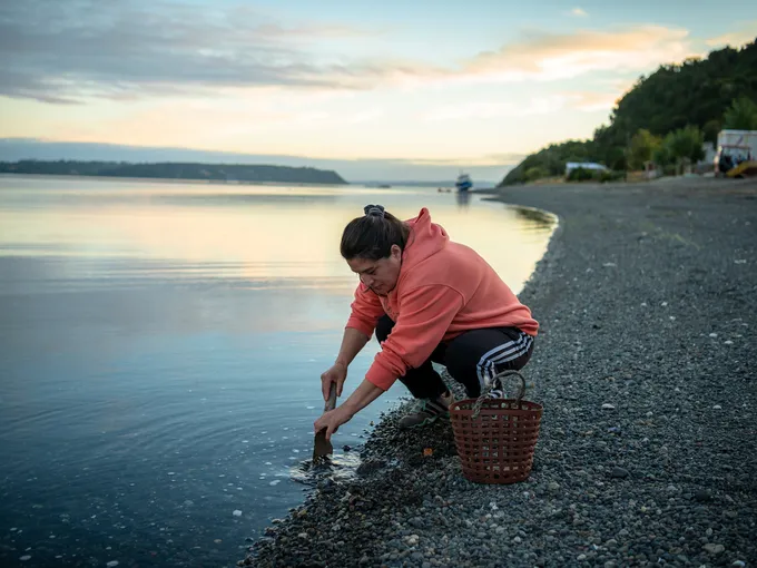 A crouching woman digs in the sand
