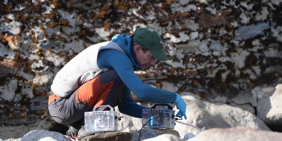 A person collects eDNA samples from a river