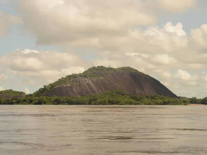 Landscape of brown and green mountain with water in foreground