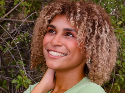 Emmy Scott wears a green shirt and looks out of the frame with a smile on her face