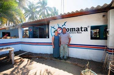 Couple stands in front of building with sign Ecomata