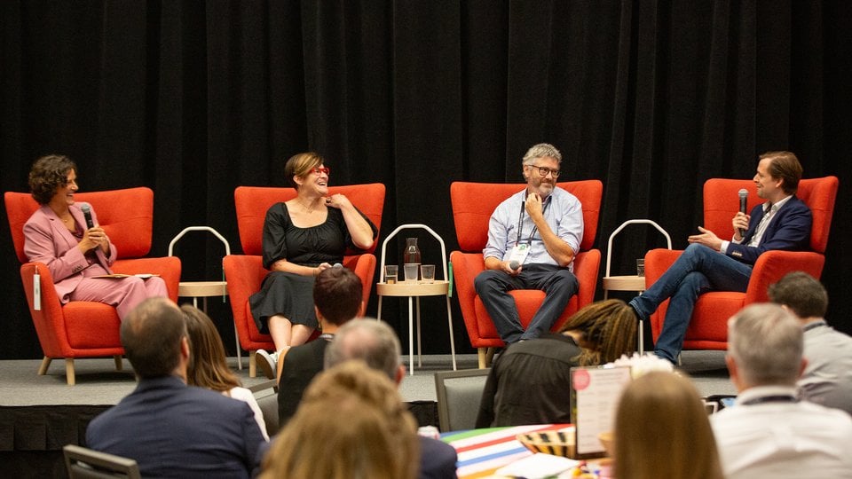 Four people sitting on stage addressing the crowd