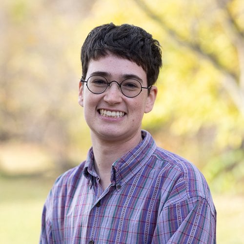 SJ Schanwald in a blue plaid shirt with a fall background