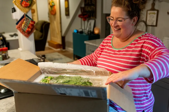 Woman opening box of vegetables