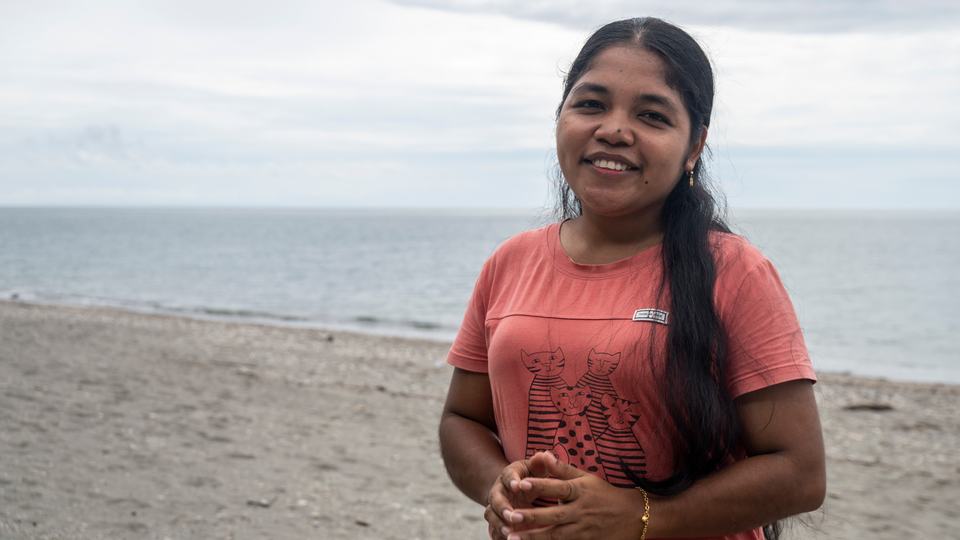 A girl on the beach smiles at the camera