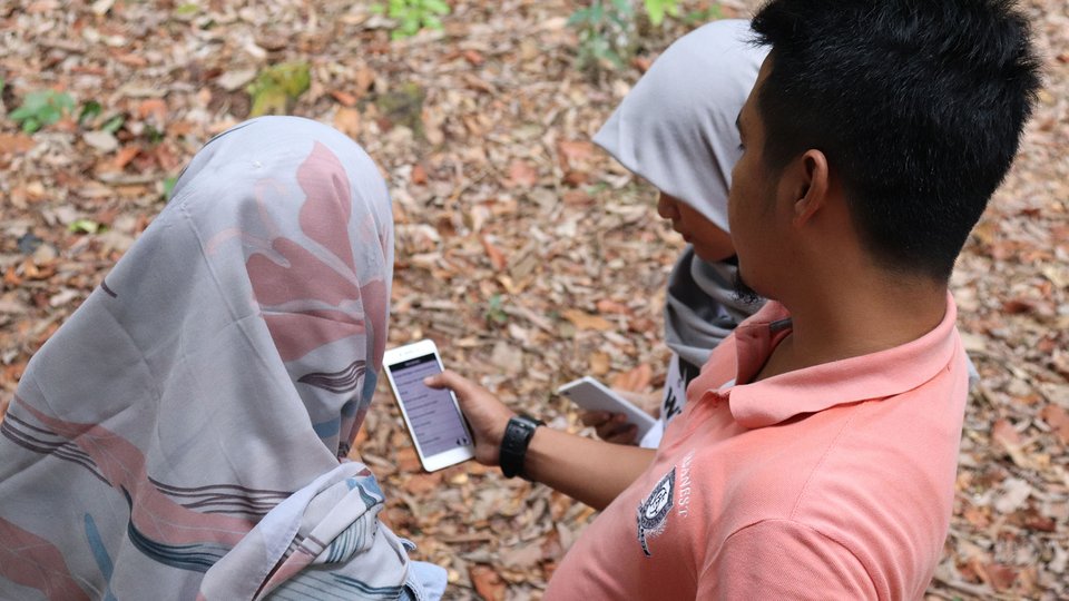 Three people look down at a phone with SMART technology