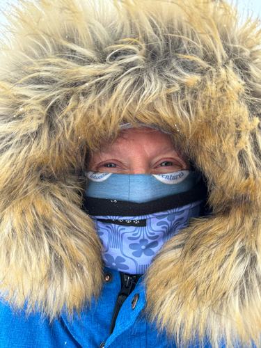 A woman with a fur hood and a blue face covering
