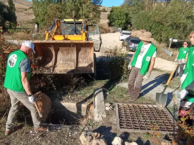 Workers and a front loader working to fill hole