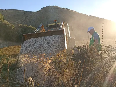 A loader dumps gravel into a hole