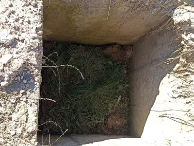 A square cement-lined hole in the ground