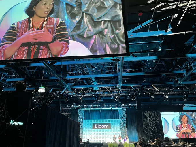 A large projector screen in a conference hall showing Jing Tauli Corpuz speaking