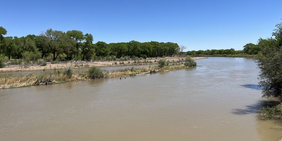 The Rio Grande river with natural muddy water, surrounded by it's green, tree lined banks.