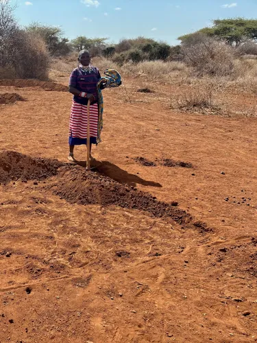 A female farmer stands next to half-moon shaped areas of fertile soil