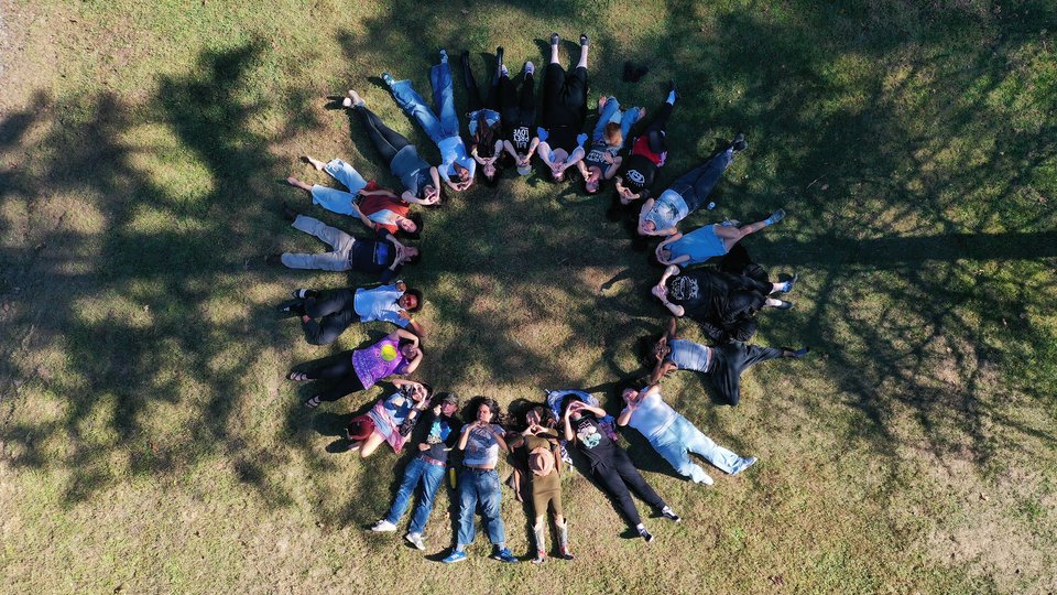 A group of people lie on their backs in the grass forming a circle