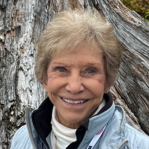 Judy Waterman smiles at the camera with a tree behind her