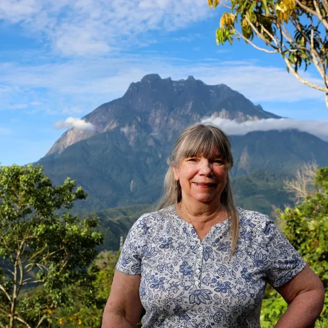 Dr. Kathy MacKinnon stands in front of Mt. Kinabalu